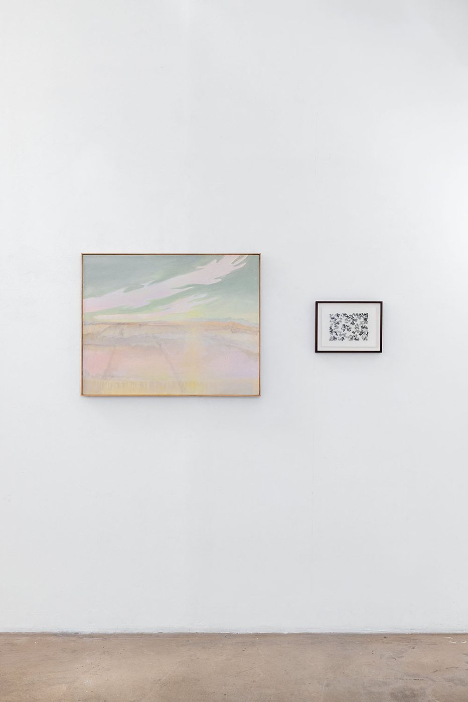 Un grand paysage peint et un petit dessin encadré, sur un mur clair